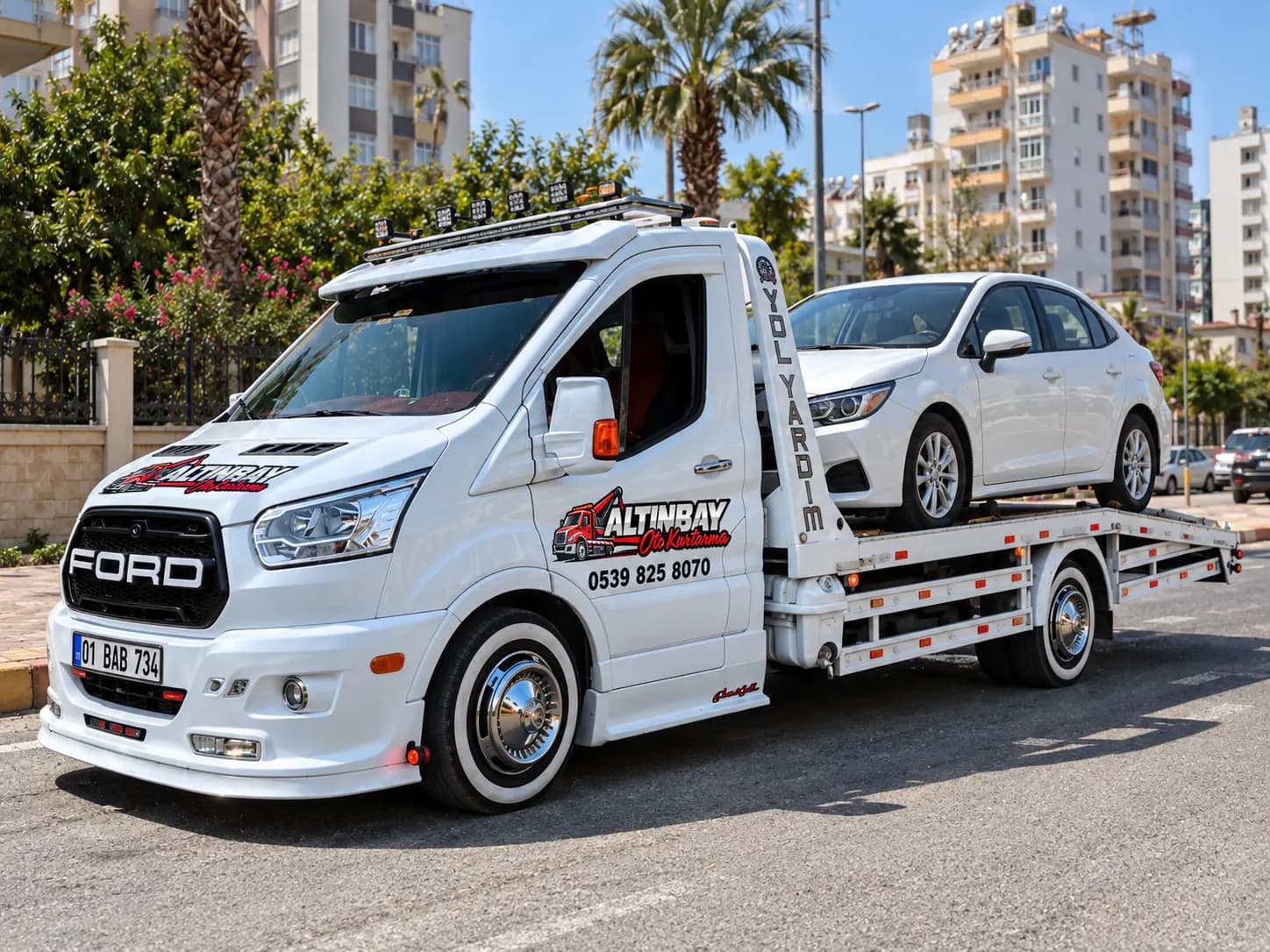 Beyaz bir otomobili düz yataklı çekici üzerine yükleyen operatör, gün ışığında