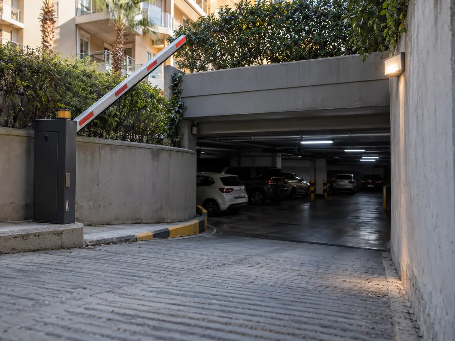 Bir sitenin kapalı otopark rampası ve bariyeri, içeride park etmiş araçlar