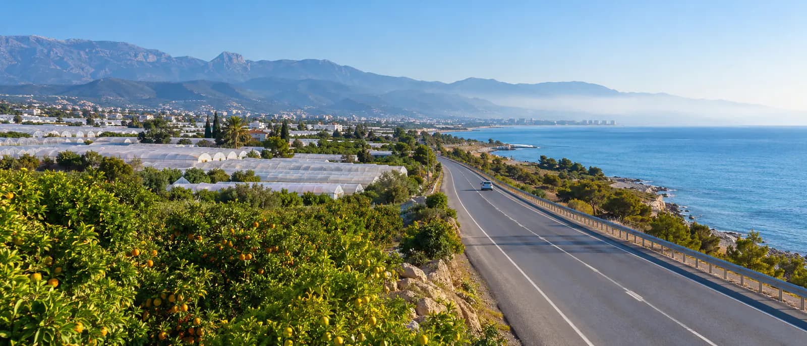 Akdeniz kıyısına paralel uzanan sahil yolu, yol kenarında seralar ve narenciye bahçeleri