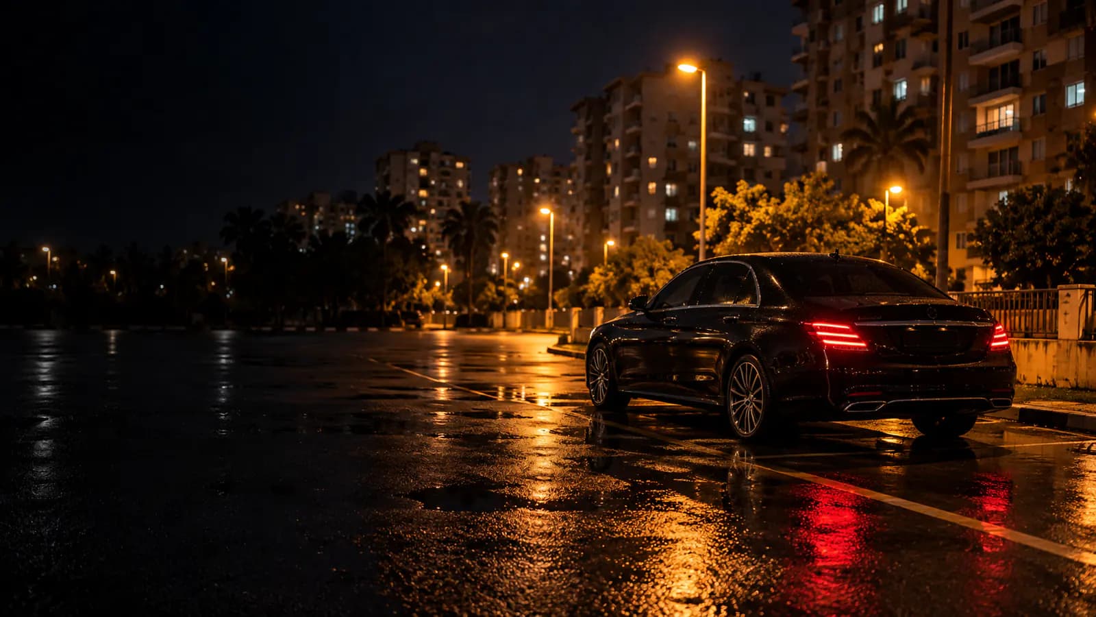 Geceleyin aydınlatılmış açık bir otoparkta duran, kaputu kapalı tek bir otomobil